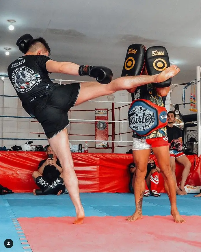 Aluno da AAZIZ Fight Club aplicando chute alto no aparelho durante treino de Muay Thai